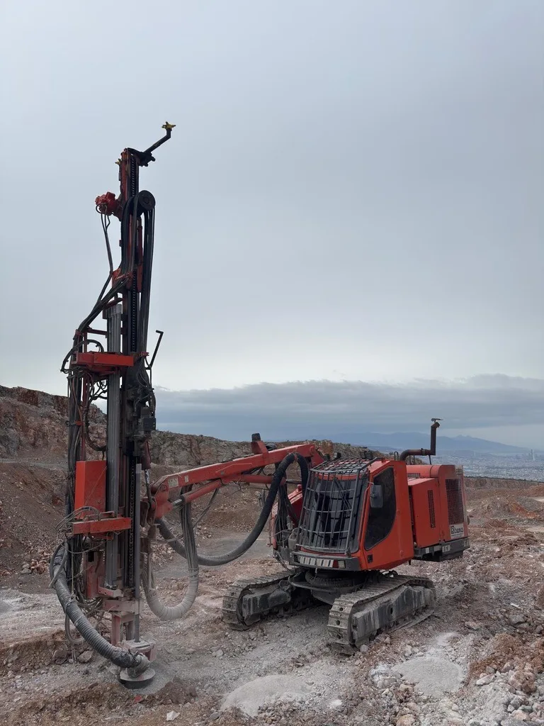 Taş ocağı basamağında çalışan kırmızı paletli delgi makinesi
